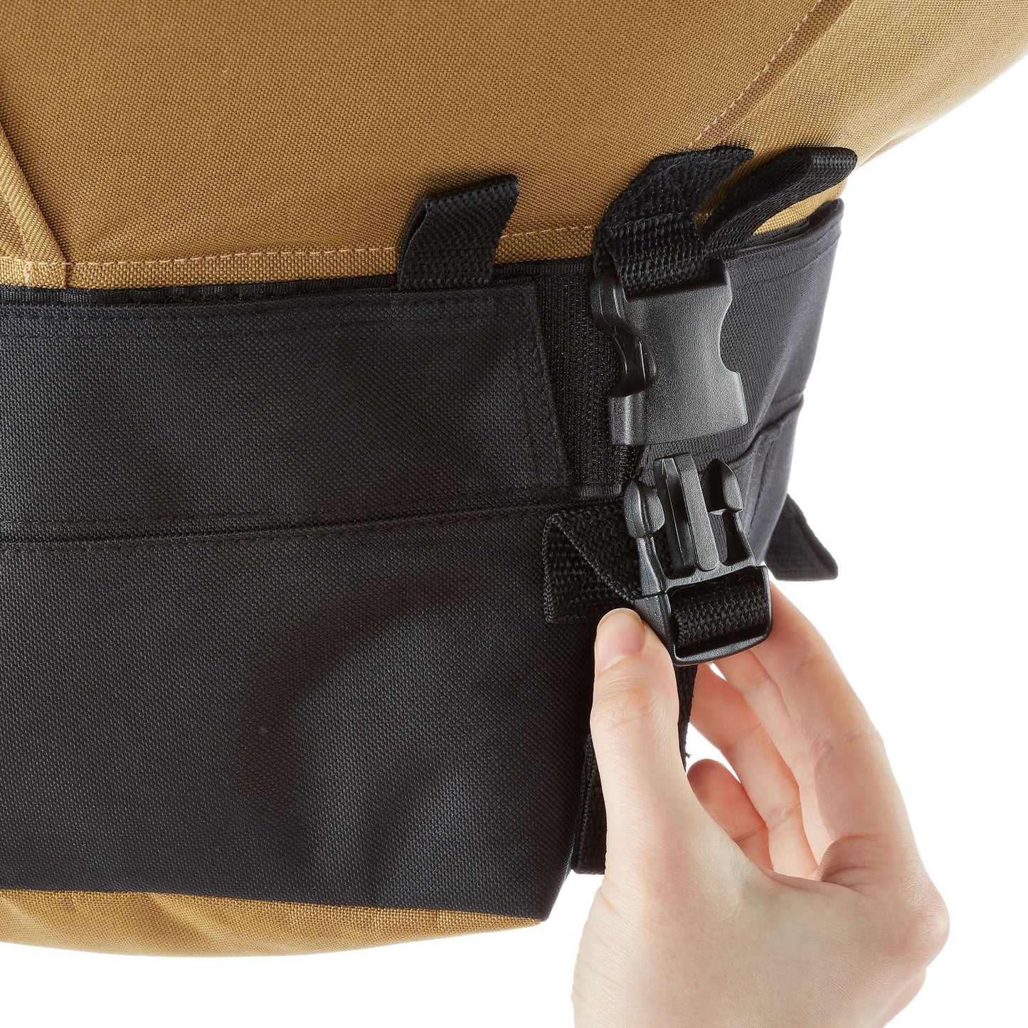 Hand opening a black buckle on the bottom of the Urban Worm Bag. 