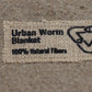 Close up of the label for 'Urban Worm Blanket' with '100% Natural Fibers' noted on the label.