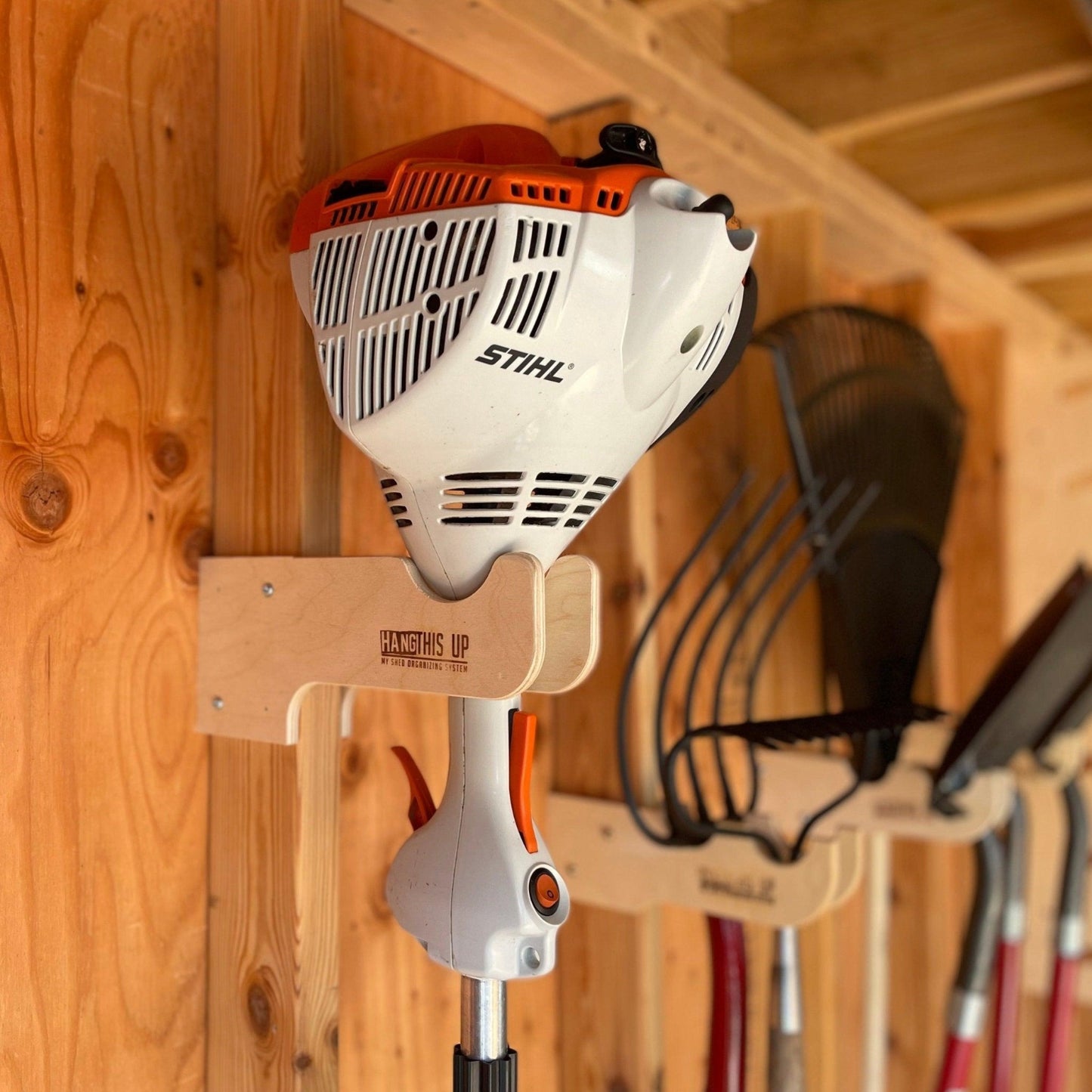 Close-up of a weed whacker organizer  installed on the stud and a weed whacker in the rack.