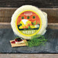 Block of Dill Havarti cheese presented on a serving platter with decorative elements such as herbs and the cheese spread on a cracker topped with jam