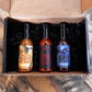 Pepper Joe's Carolina Reaper hot sauce gift box that includes one bottle each of Blueberry Reaper, Pineapple Reaper, and Carolina Reaper packaged inside gift box on a rustic background.