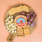 Wooden board with sliced cheese and cured meats on a peach background