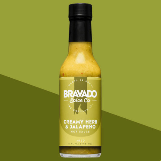 Bottle of creamy herb and jalapeno hot sauce on a green background