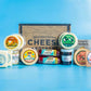 An assortment of gourmet cheeses, meats, and crackers displayed in front of a wooden box 