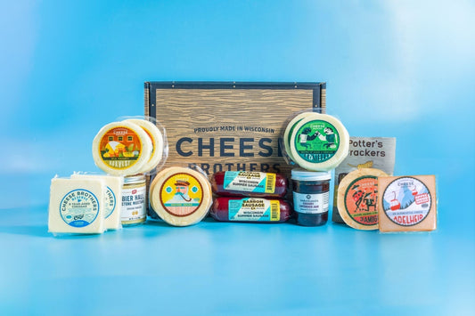 An assortment of gourmet cheeses, meats, and crackers displayed in front of a wooden box 