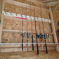 Stud-mounted fishing rod organization rack holding multiple fishing rods, installed on unfished shed ceiling. 