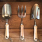 Set of three gardening tools with wooden handles on a wooden background