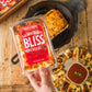 golden baked bliss cheese held over cast iron pan and other sliced cheese on wood table