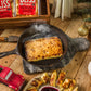 golden baked bliss cheese smoking in cast iron pan on wooden table with Christmas decor