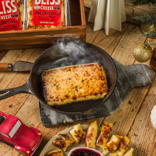 golden baked bliss cheese smoking in cast iron pan on wooden table with Christmas decor