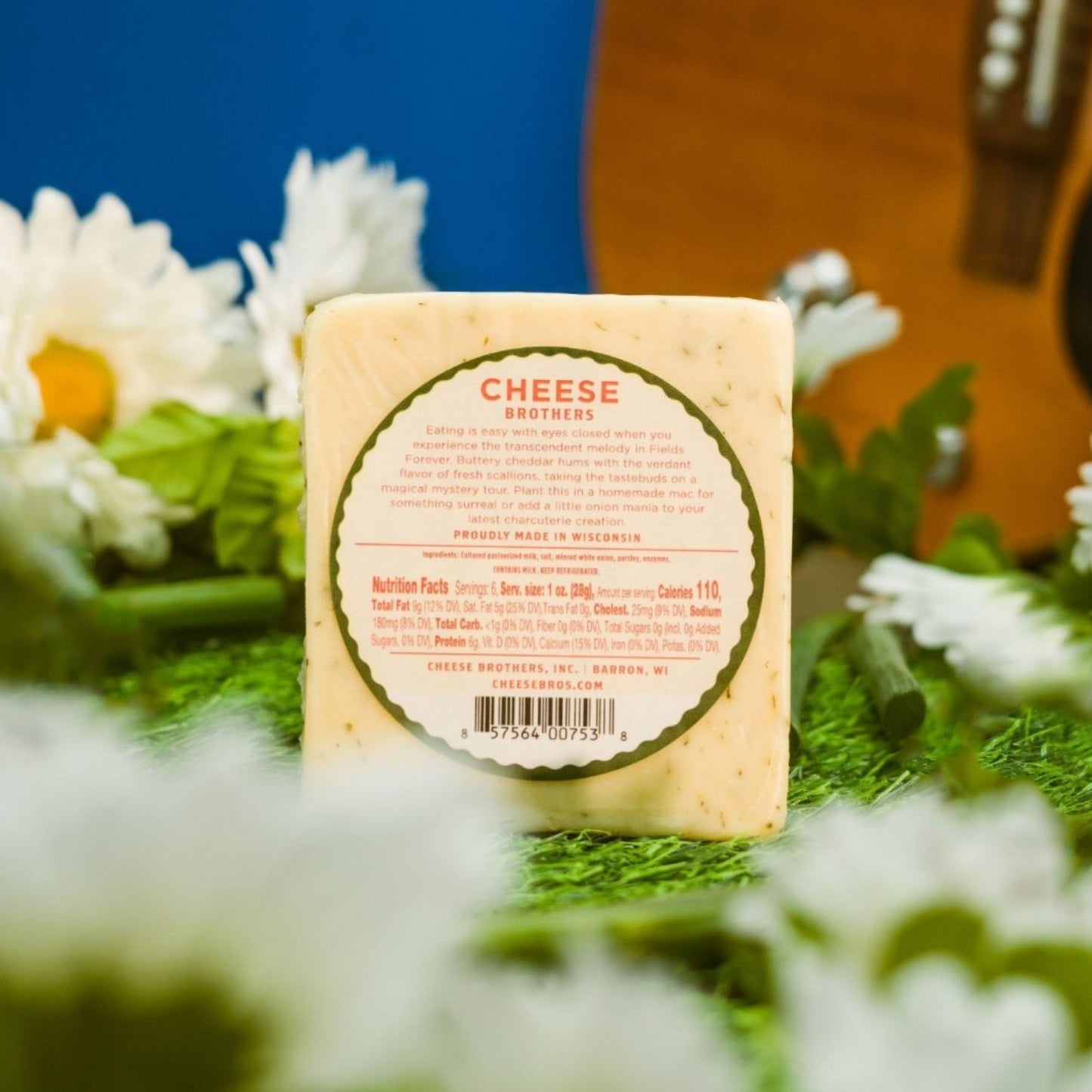 Green onion cheddar cheese block ingredient and nutrition label presented on a field of grass with decorate elements such as white daisy flowers and green onion