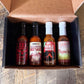 Pepper Joe's Habanero hot sauce gift box that includes one bottle each of XXX Habanero, Garlic Habanero, Mango Habanero, and Tropical Habanero inside gift box on a rustic background.