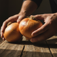Hands holding Texas Super Sweet onion on wooden countertop used to display onion seeds for sale