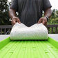 Person holding hemp grow mat above green seed tray showing underside of soilless growing medium used for hydroponics and microgreens