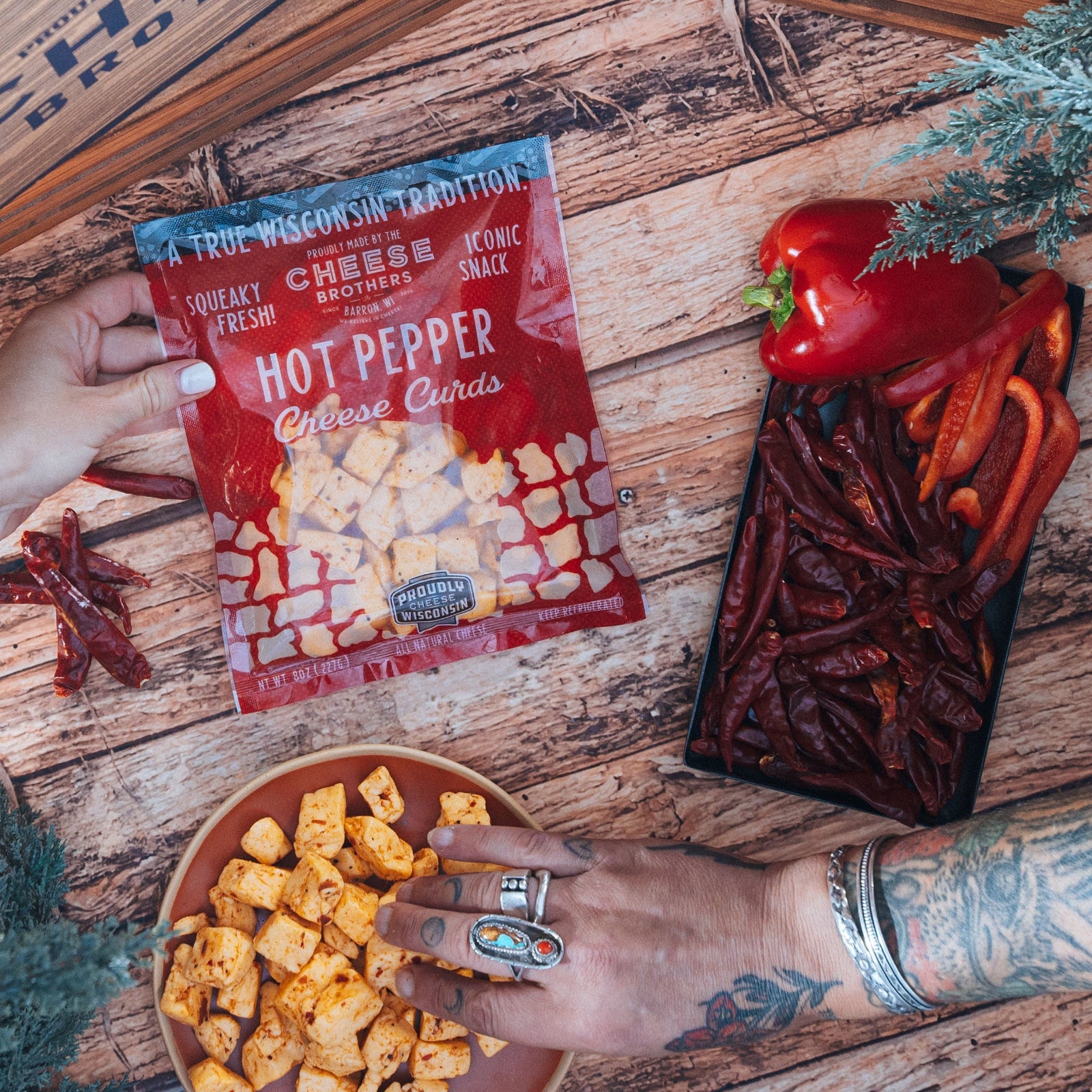 hand holding hot pepper cheese curds package over bowl of cheese curds on wooden surface