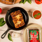 Italian Baked Bliss Cheese in cast iron pan surrounded by peppers, tomatoes and basil
