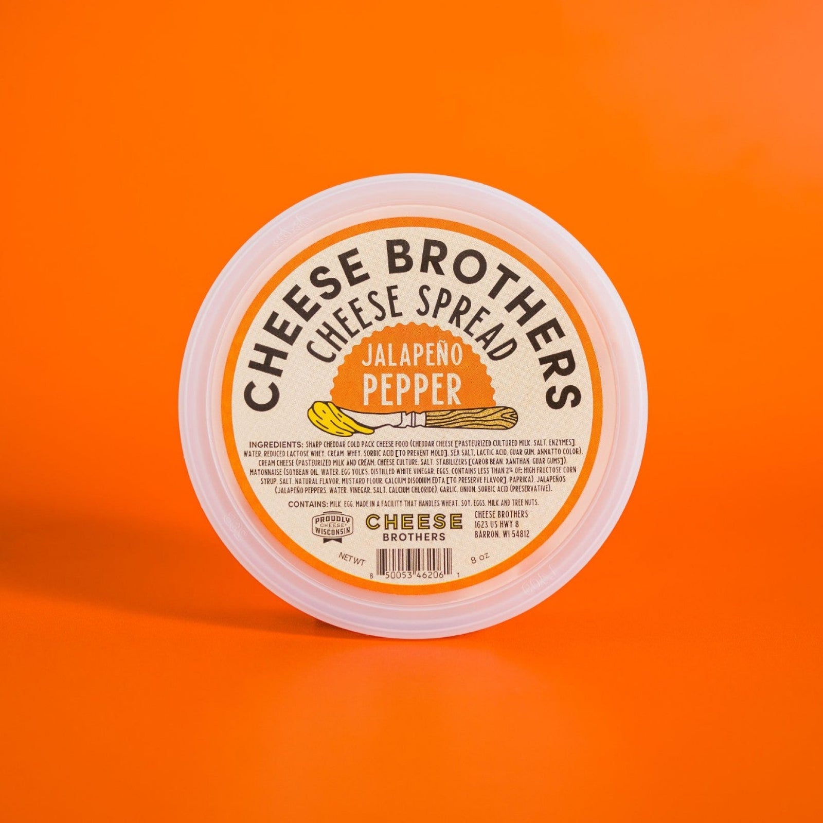 Container of jalapeno pepper cheese spread on orange background