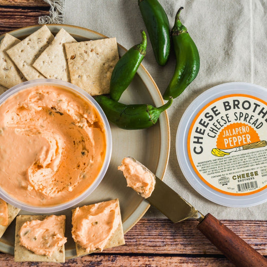 Jalapeno Pepper Cheese Spread on top of crackers with jalapenos on a wood table
