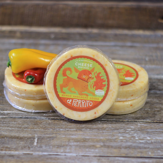 mango habanero gouda cheese wheels stacked on one another on a wooden surface