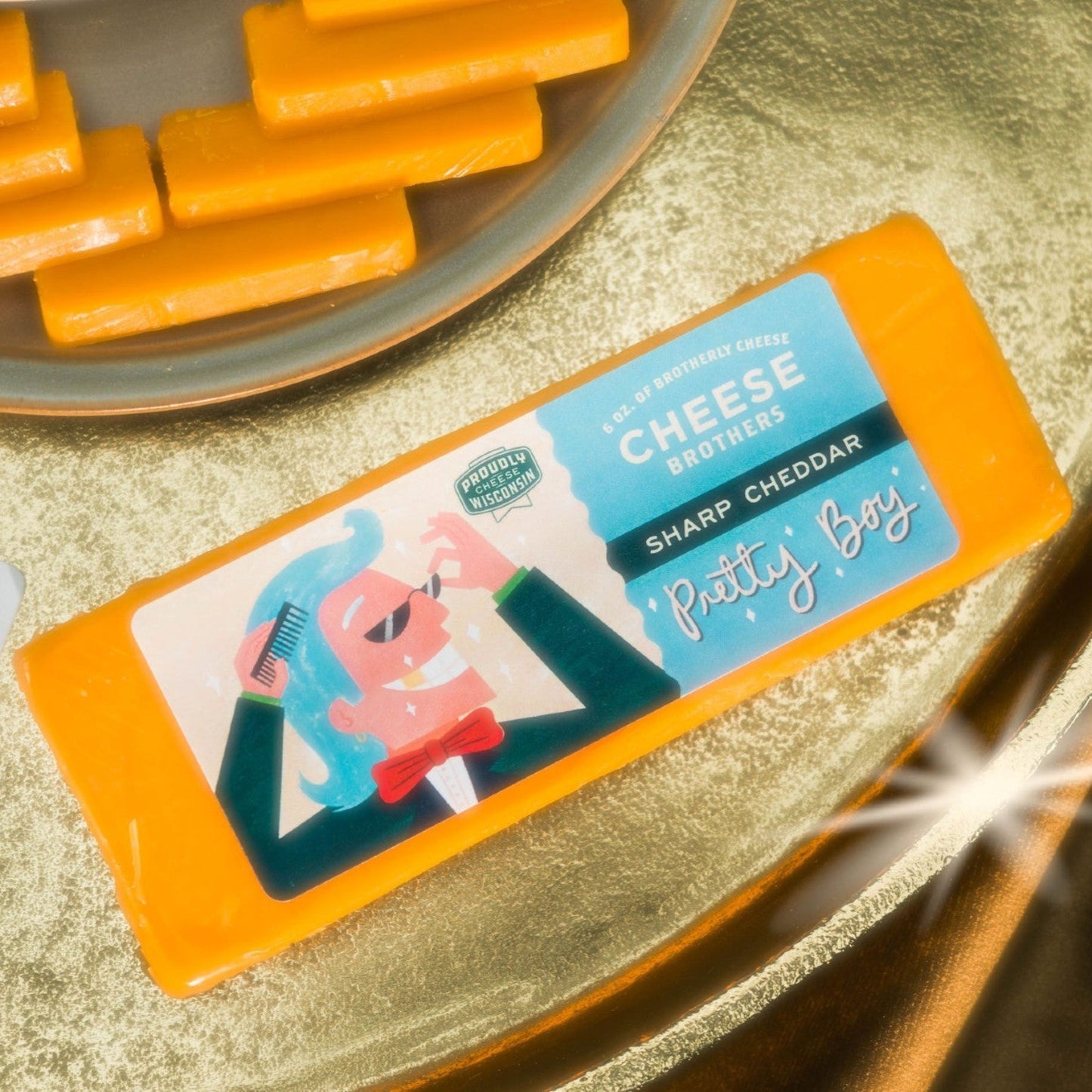 A packaged sharp cheddar cheese displayed on a golden surface, with the branding 'Pretty Boy' visible on the packaging.