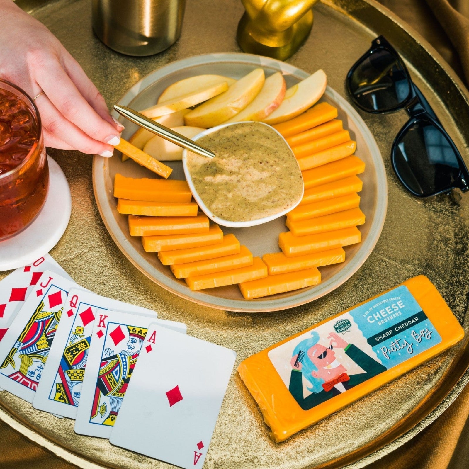 Sliced Pretty Boy Cheddar cheese on a plate with apples and dip