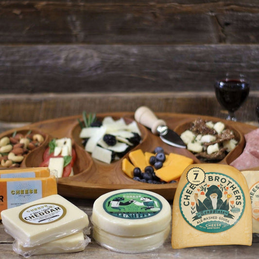 assorted sharp cheese blocks with charcuterie display on wooden surface