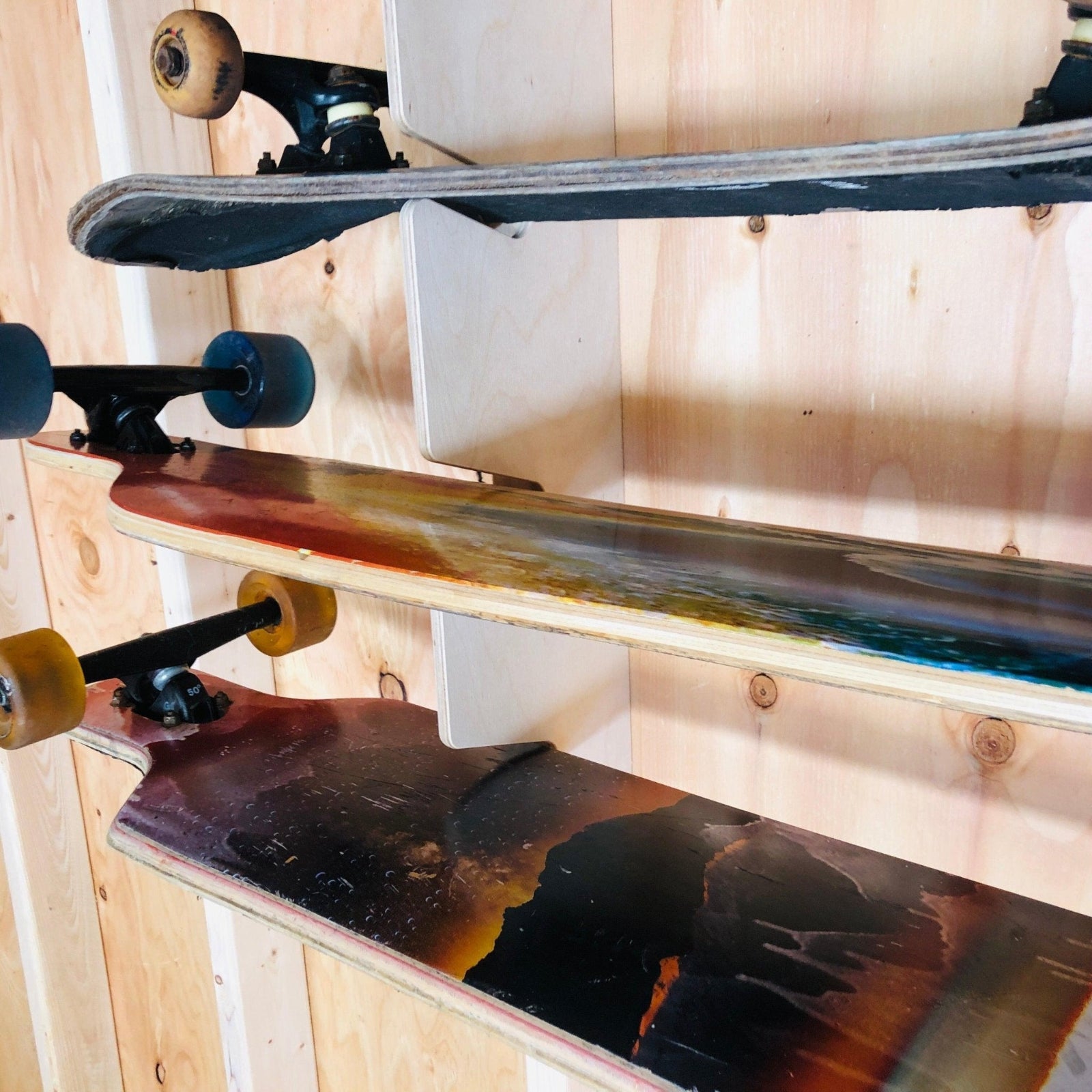 Close-up of a skateboard organizer wood grain installed on the stud and skateboards in the rack.