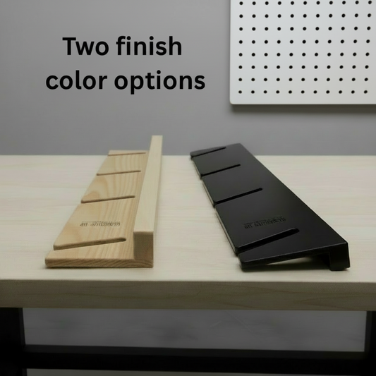 Two skateboard organizer finish options displayed on a workbench, featuring a natural wood slotted rack and a black slotted rack for organizing skateboards and longboards.
