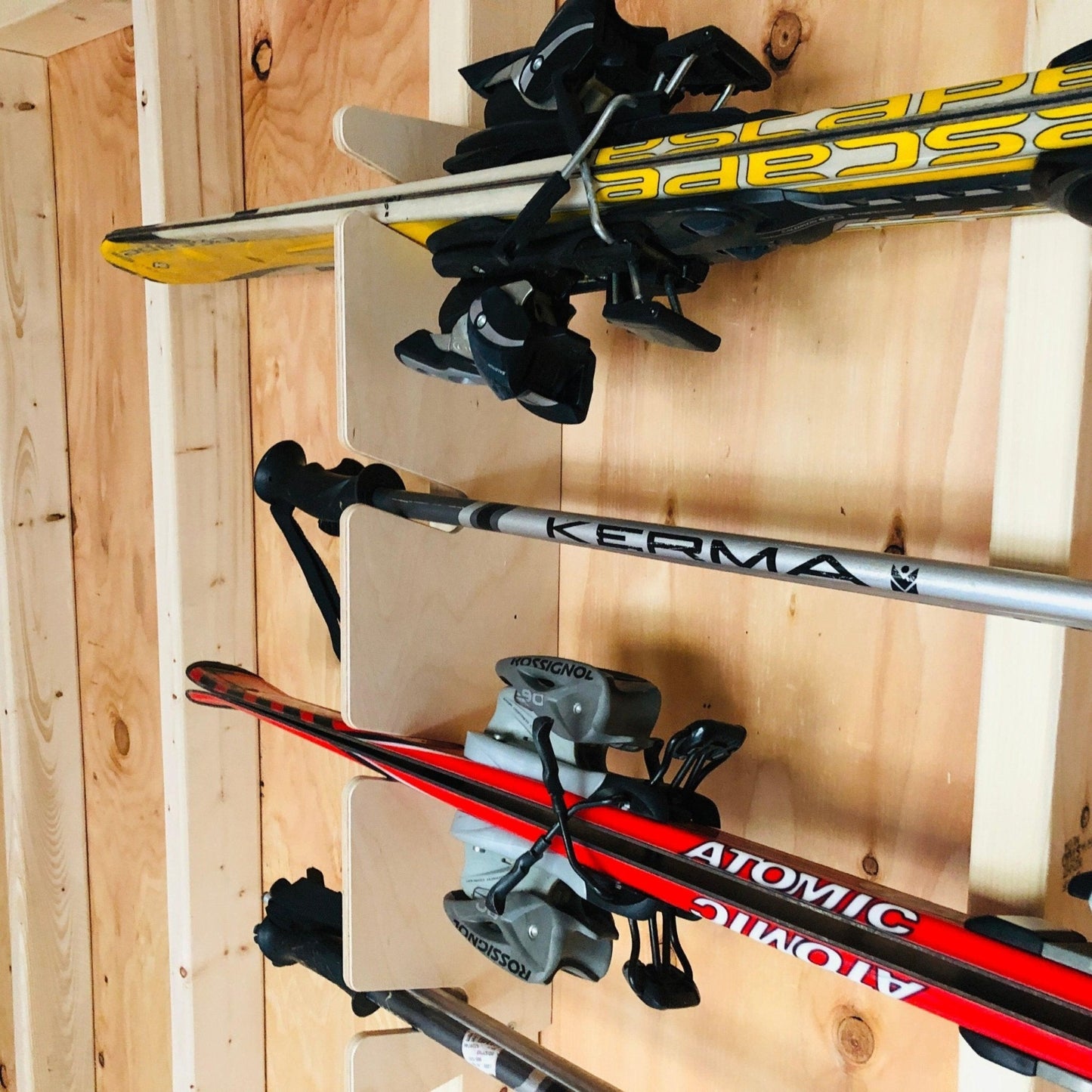 Close-up of a ski organizer wood grain installed on the stud with snow skis and snow poles in the rack.