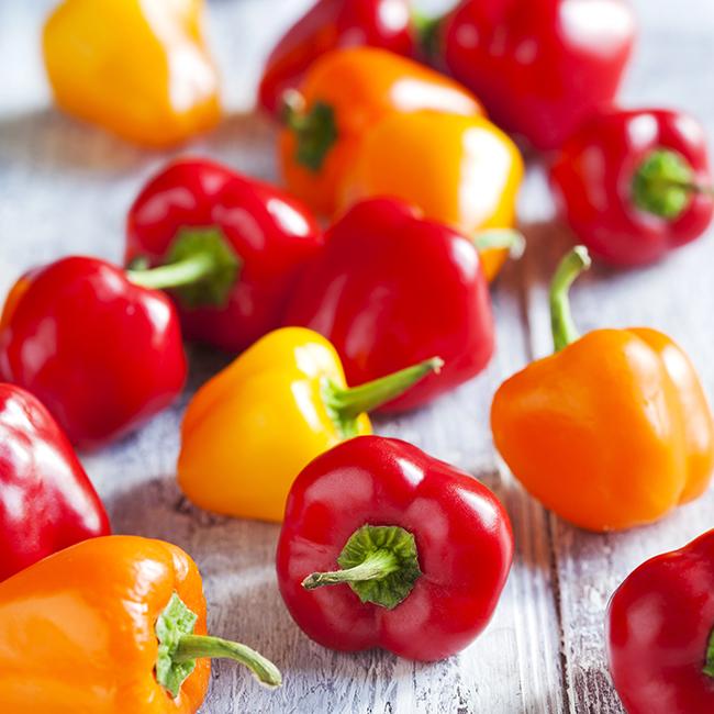 Pepper Joe's Mini Bell pepper seeds - pile of sweet small bell peppers on wooden table image